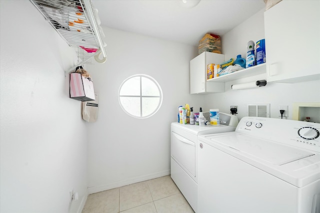 laundry room featuring washer and clothes dryer, light tile patterned flooring, and cabinets