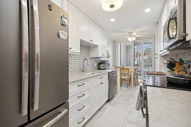 kitchen with ceiling fan, white cabinetry, appliances with stainless steel finishes, and tasteful backsplash