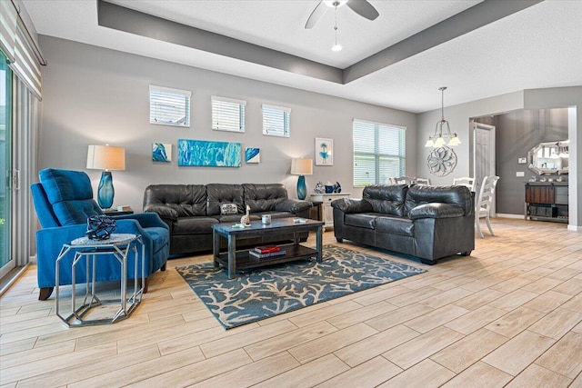 living room with ceiling fan with notable chandelier and light wood-type flooring