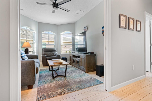 living room featuring ceiling fan, light hardwood / wood-style floors, and a textured ceiling