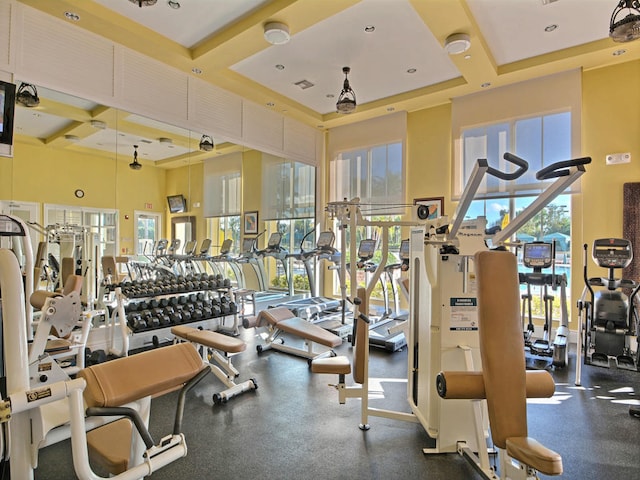 workout area with a towering ceiling and coffered ceiling