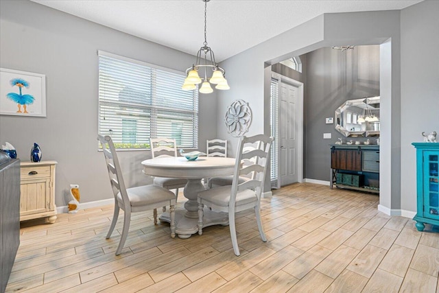 dining area featuring a chandelier, a textured ceiling, and light hardwood / wood-style floors