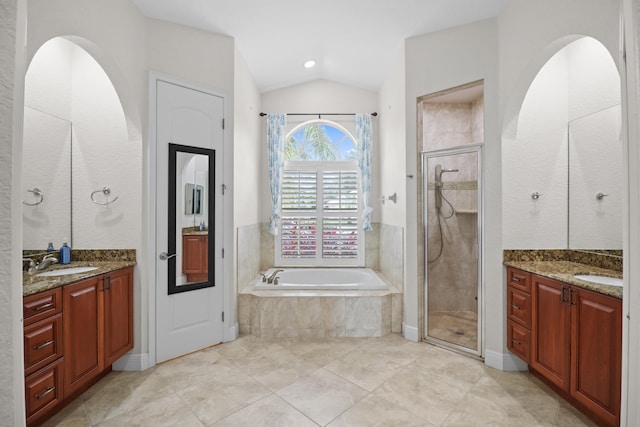 bathroom featuring vanity, independent shower and bath, and vaulted ceiling