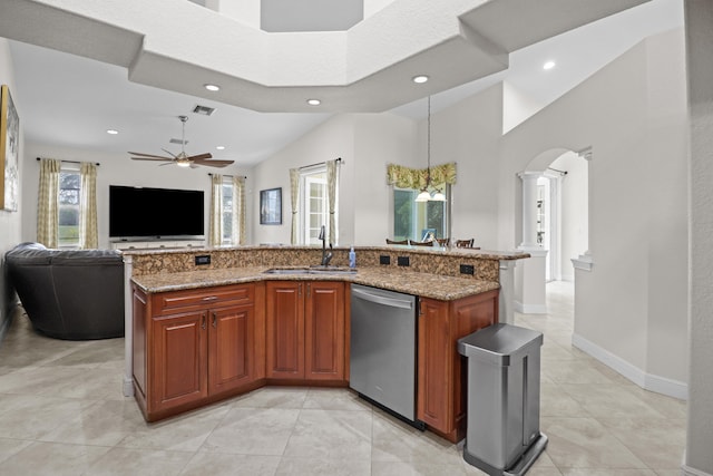 kitchen with light stone counters, stainless steel dishwasher, ceiling fan with notable chandelier, a kitchen island with sink, and sink