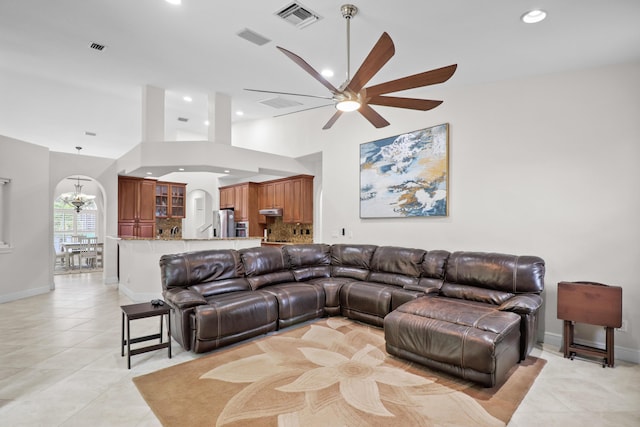 living room featuring a high ceiling, ceiling fan with notable chandelier, and light tile patterned flooring