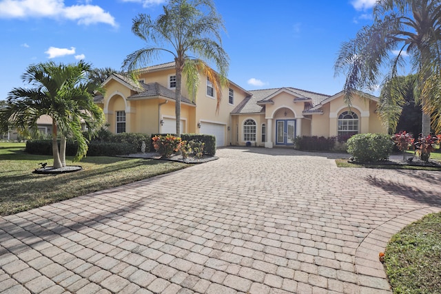 mediterranean / spanish house featuring a garage and a front lawn