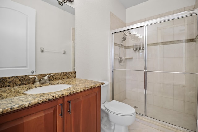 bathroom with tile patterned floors, vanity, toilet, and walk in shower