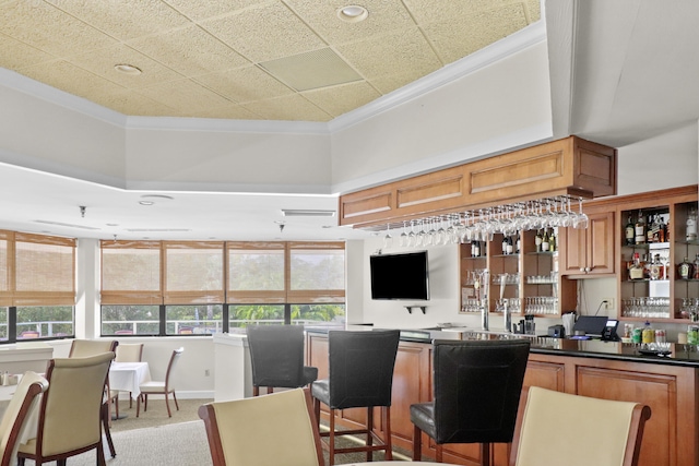 kitchen with light colored carpet, plenty of natural light, crown molding, and a breakfast bar area