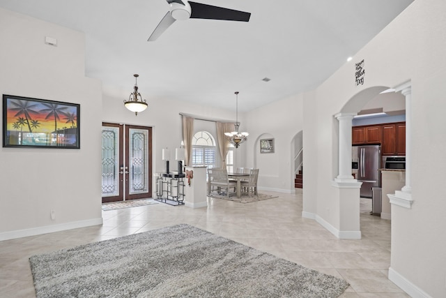 entrance foyer with ceiling fan with notable chandelier, light tile patterned floors, and french doors