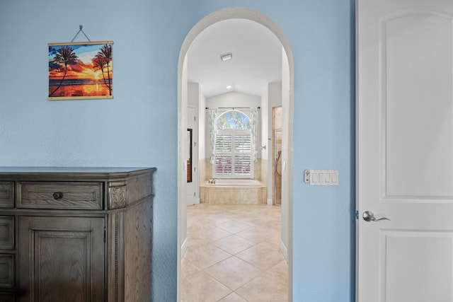 hallway featuring light tile patterned flooring and lofted ceiling