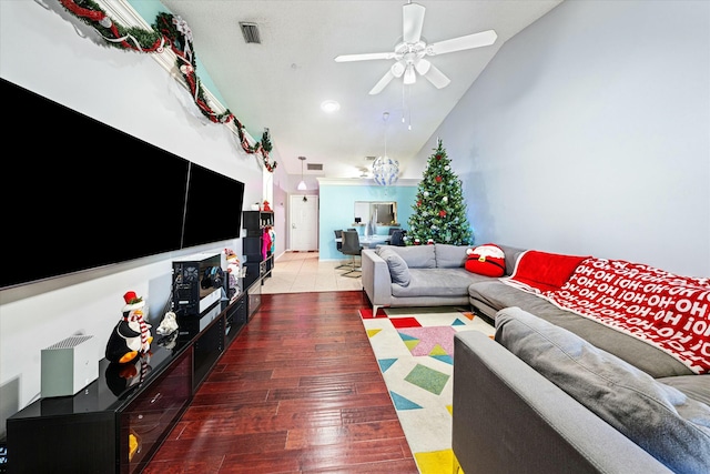 living room featuring ceiling fan with notable chandelier, wood-type flooring, and lofted ceiling