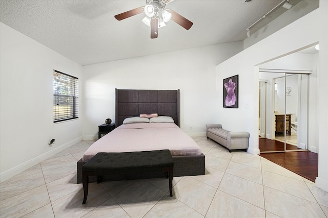 tiled bedroom with a textured ceiling, a closet, track lighting, and ceiling fan