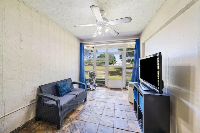 living area featuring ceiling fan and a textured ceiling