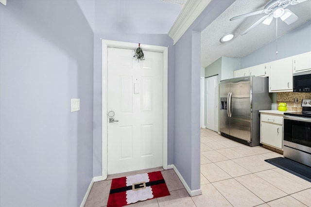 kitchen featuring decorative backsplash, light tile patterned floors, a textured ceiling, white cabinetry, and stainless steel appliances