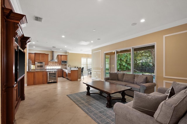 tiled living room with sink, ornamental molding, and beverage cooler