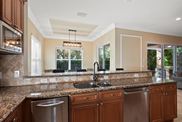 kitchen with ornamental molding, stainless steel appliances, sink, and hanging light fixtures