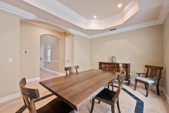 dining room with ornamental molding and a raised ceiling