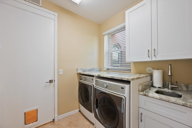 laundry area featuring sink, light tile patterned floors, cabinets, and washing machine and clothes dryer