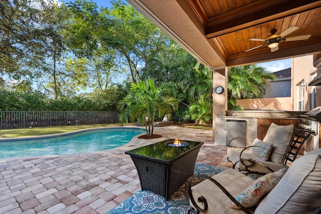 view of pool with ceiling fan, an outdoor kitchen, a bar, and a patio