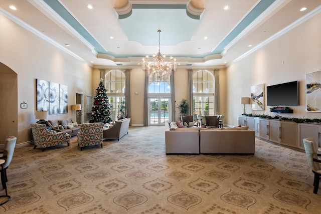 carpeted living room with crown molding, a tray ceiling, a chandelier, and a high ceiling