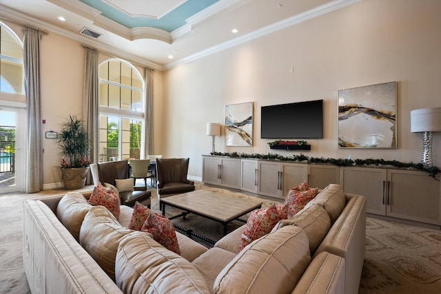 carpeted living room with a tray ceiling, crown molding, plenty of natural light, and a high ceiling