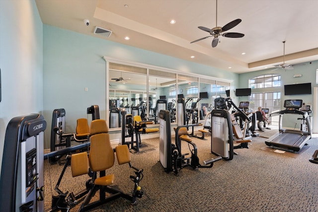 workout area featuring ceiling fan and a tray ceiling