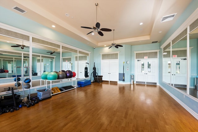 exercise room with hardwood / wood-style floors and a tray ceiling