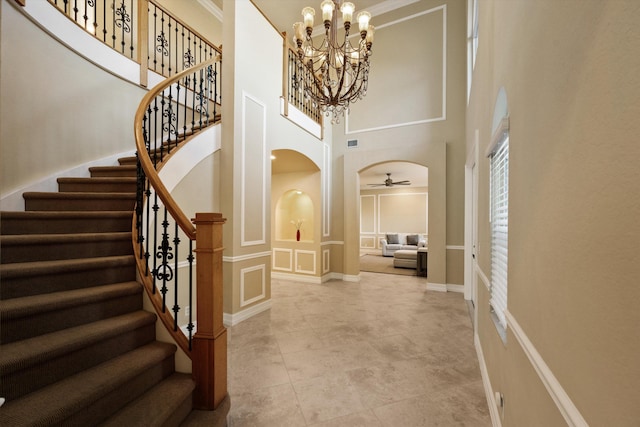 foyer entrance with a towering ceiling and ceiling fan with notable chandelier