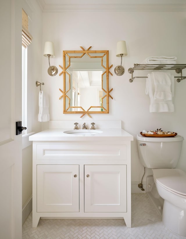 bathroom with vanity, ornamental molding, and toilet