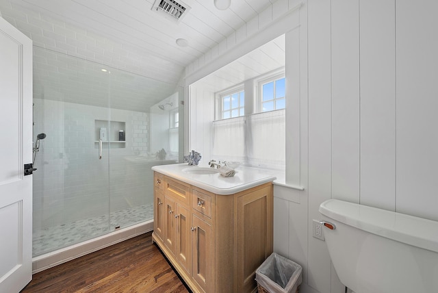 bathroom featuring vanity, vaulted ceiling, hardwood / wood-style floors, toilet, and a shower with shower door