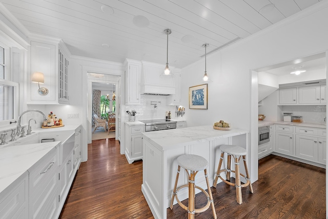 kitchen featuring white cabinets, sink, dark hardwood / wood-style floors, light stone countertops, and a kitchen bar