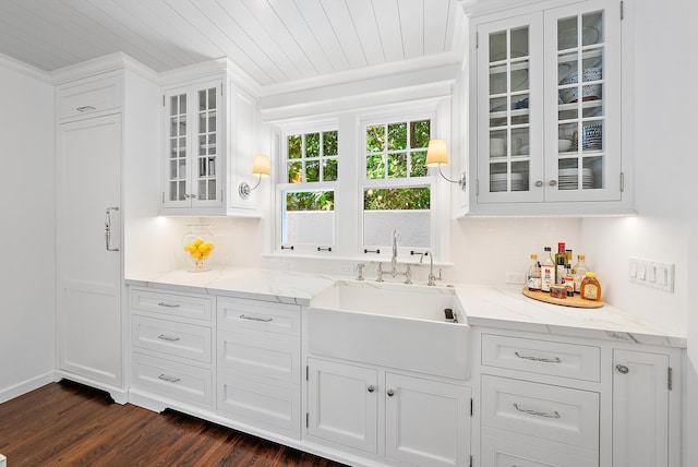 bar with dark hardwood / wood-style flooring, light stone counters, white cabinetry, and sink