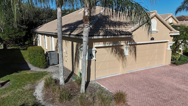 view of side of home with central AC unit and a garage