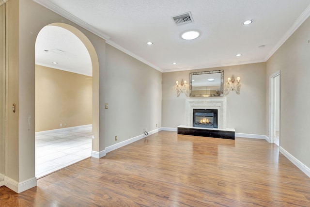 unfurnished living room featuring wood-type flooring, crown molding, and a premium fireplace