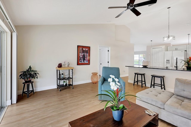 living area featuring light wood-type flooring, ceiling fan, baseboards, and lofted ceiling