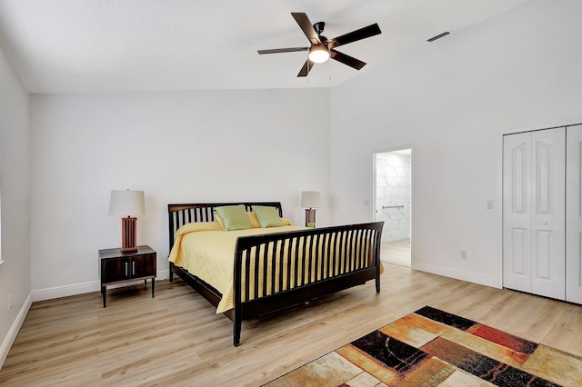 bedroom with lofted ceiling, visible vents, light wood-style flooring, ensuite bath, and baseboards