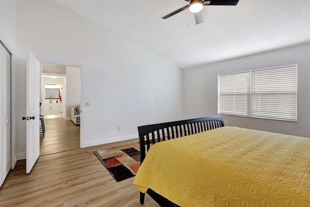 bedroom featuring baseboards, a ceiling fan, lofted ceiling, wood finished floors, and a closet