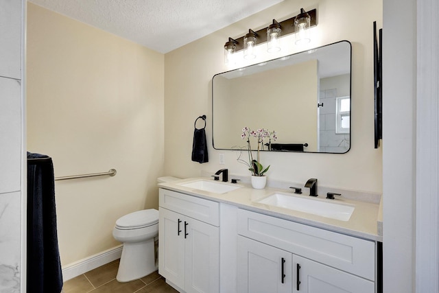 bathroom featuring double vanity, a textured ceiling, toilet, and a sink