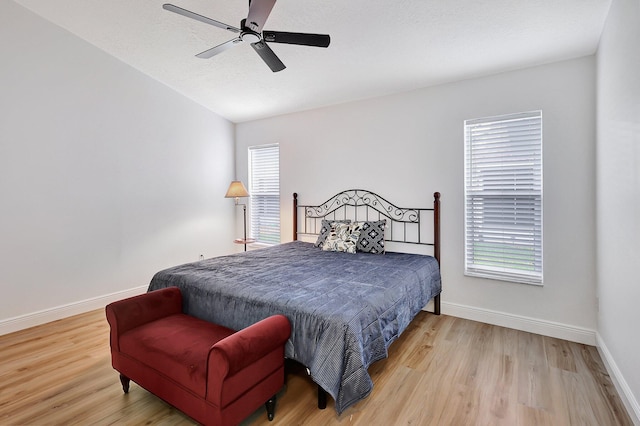 bedroom with baseboards, multiple windows, and light wood-style floors