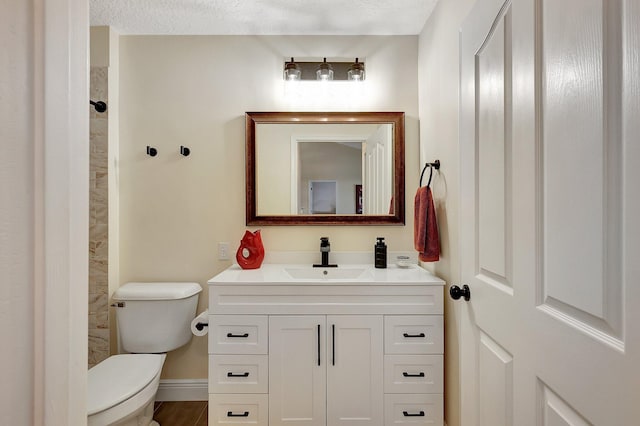 bathroom featuring baseboards, tiled shower, toilet, a textured ceiling, and vanity