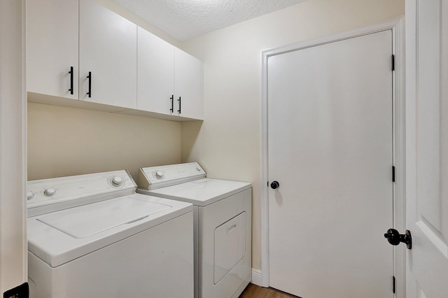 clothes washing area featuring cabinet space, a textured ceiling, and washing machine and clothes dryer