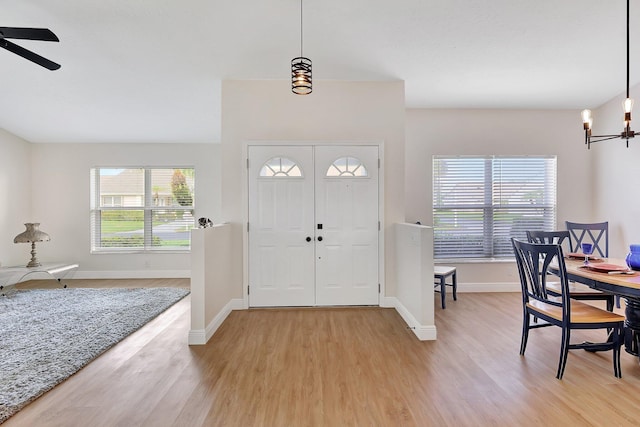 entrance foyer with light wood-style flooring, baseboards, and ceiling fan with notable chandelier