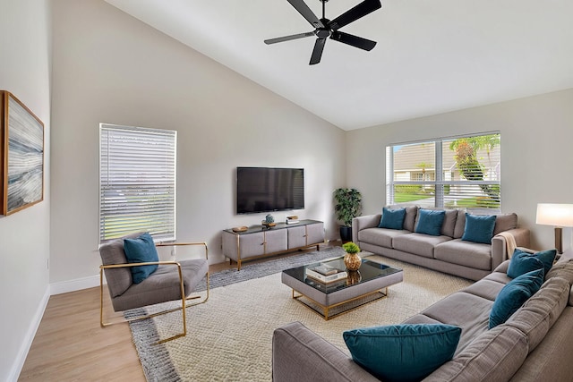 living area featuring high vaulted ceiling, light wood-type flooring, baseboards, and a ceiling fan