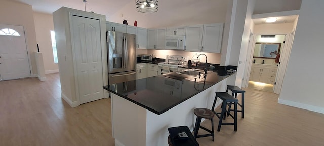 kitchen featuring stainless steel appliances, a peninsula, a sink, and a kitchen breakfast bar