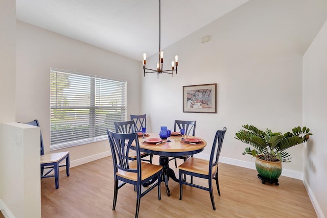 dining room featuring vaulted ceiling, light wood-type flooring, an inviting chandelier, and baseboards