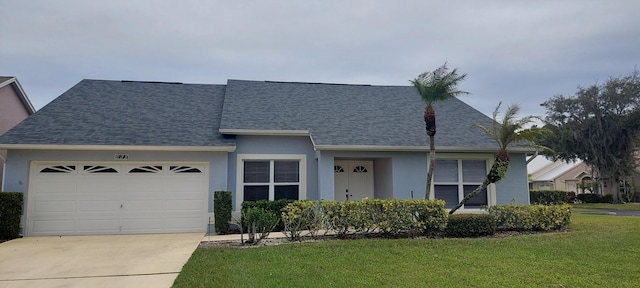 view of front of home with driveway, roof with shingles, an attached garage, a front lawn, and stucco siding