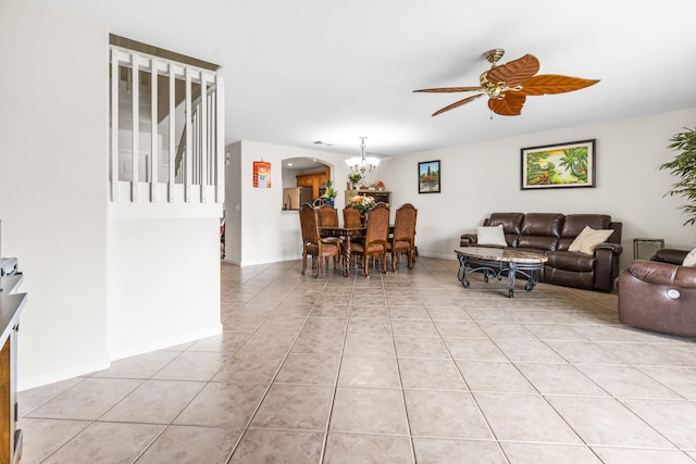 tiled living room with ceiling fan with notable chandelier