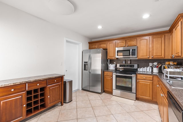 kitchen with decorative backsplash, light tile patterned floors, stainless steel appliances, and dark stone countertops