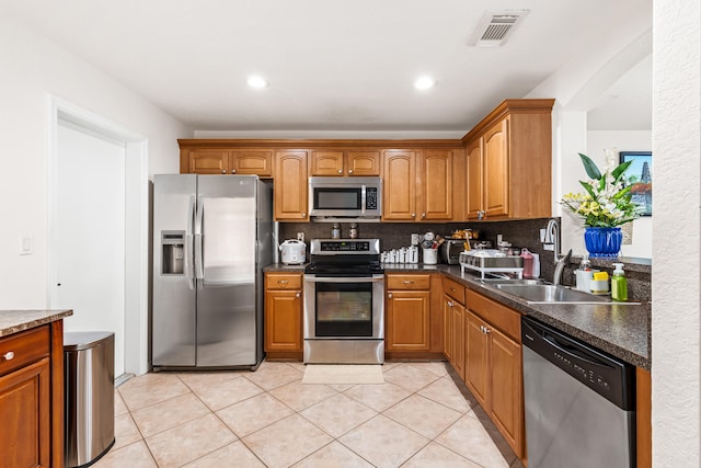 kitchen with appliances with stainless steel finishes, tasteful backsplash, light tile patterned floors, and sink