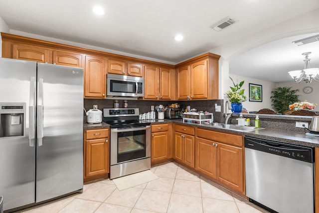 kitchen with sink, backsplash, a chandelier, light tile patterned floors, and appliances with stainless steel finishes